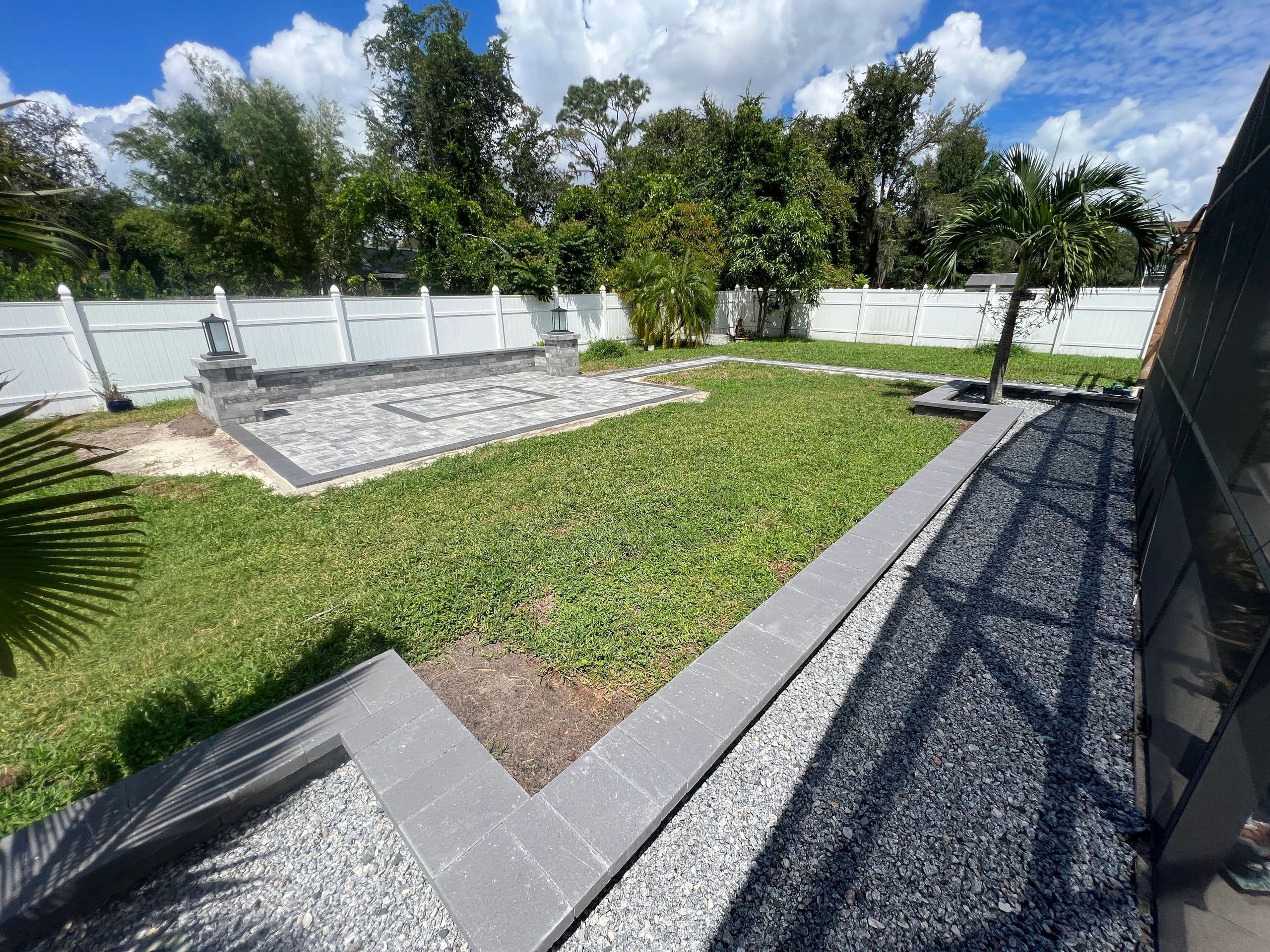 Backyard paver patio with seating wall and lantern pillars