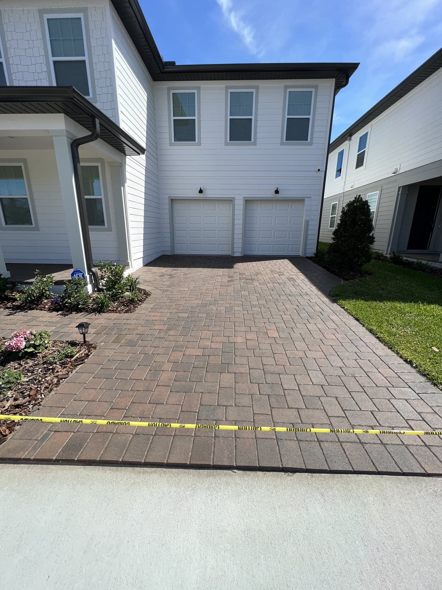 Sealed paver driveway in front of a white two-story house