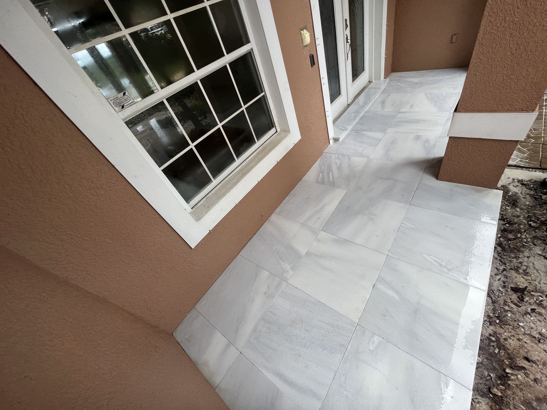 Finished travertine walkway in large format slabs running along the front of the house