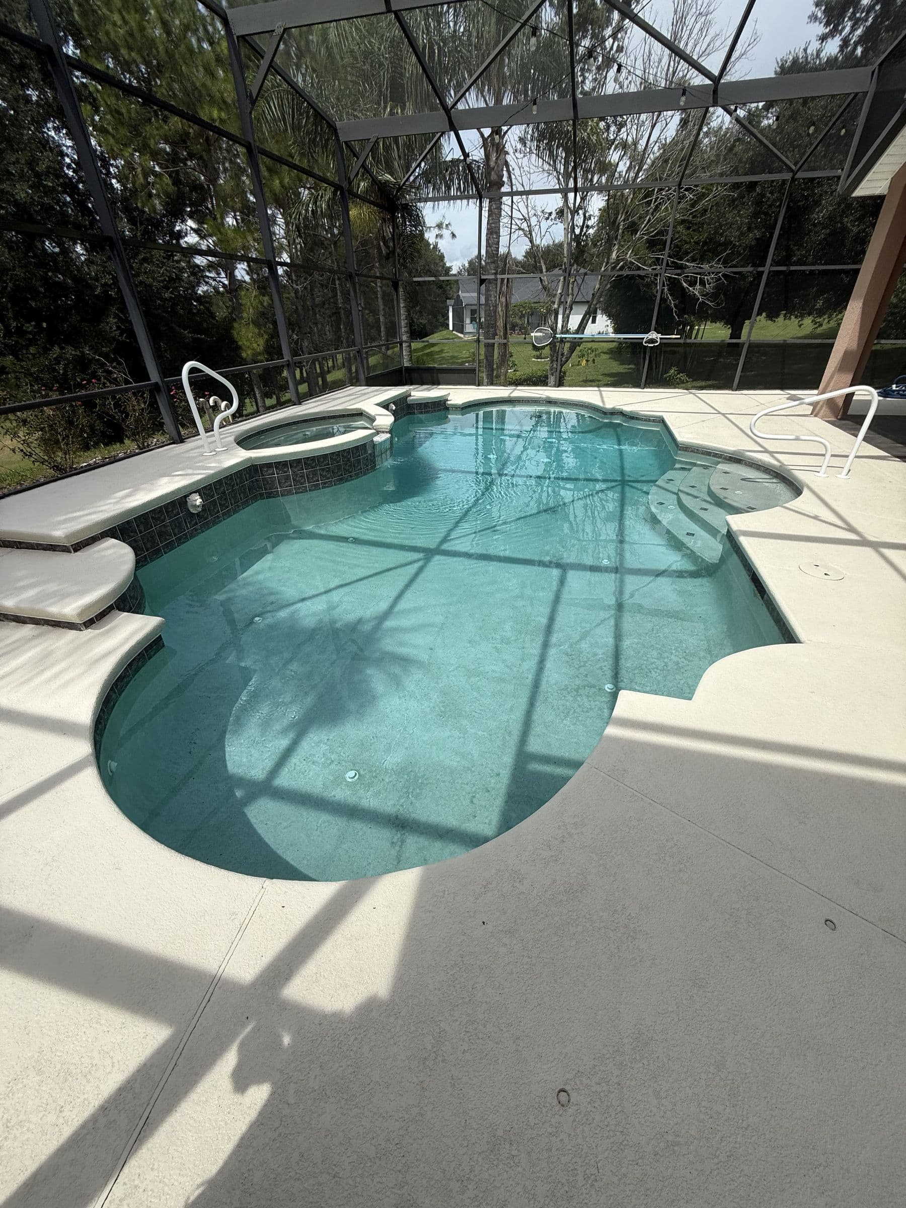 Pool before the remodel, surrounded by plain concrete decking