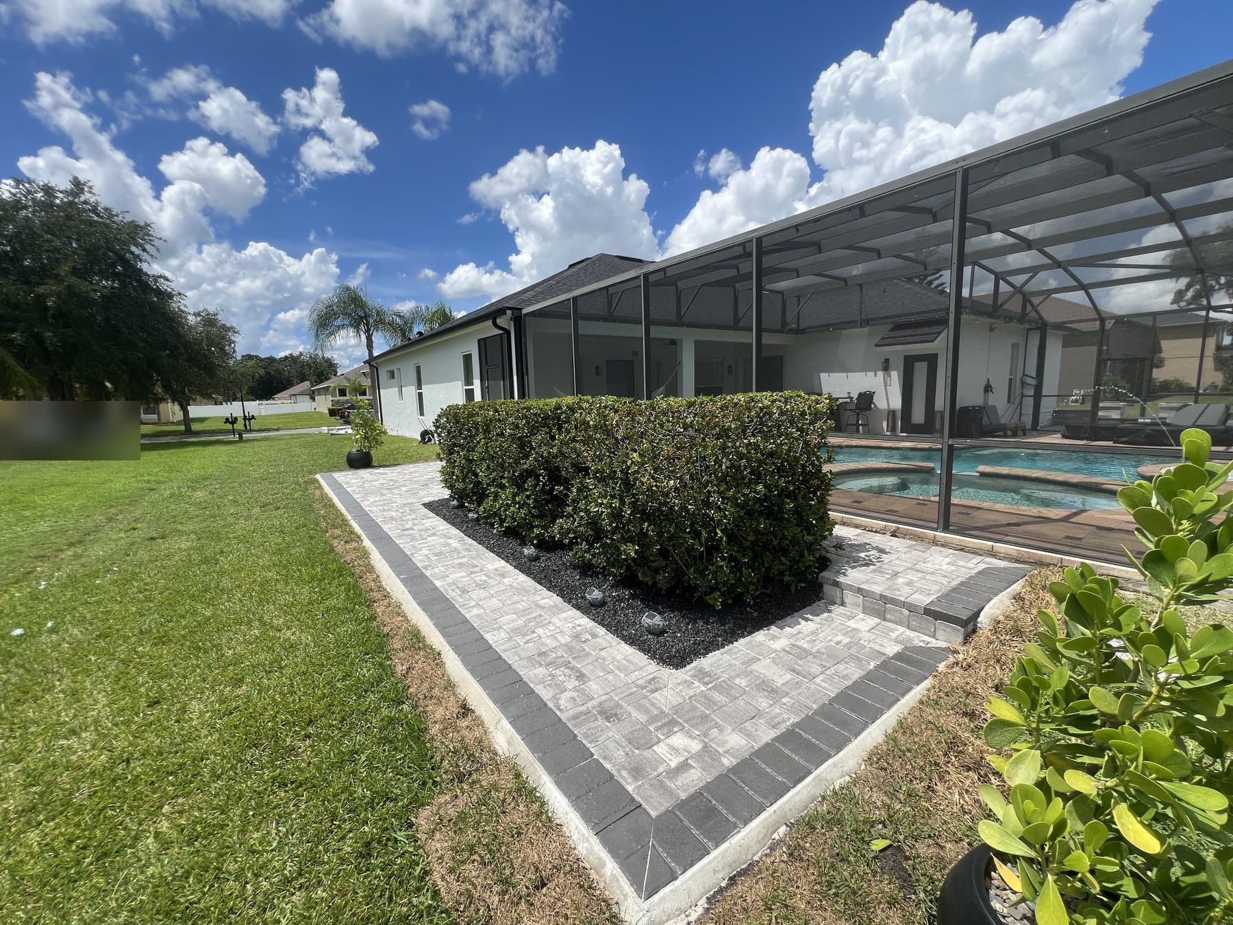 Charcoal-bordered walkway and step from the lawn up to the patio, the hedge alongside and the pool inside the enclosure behind